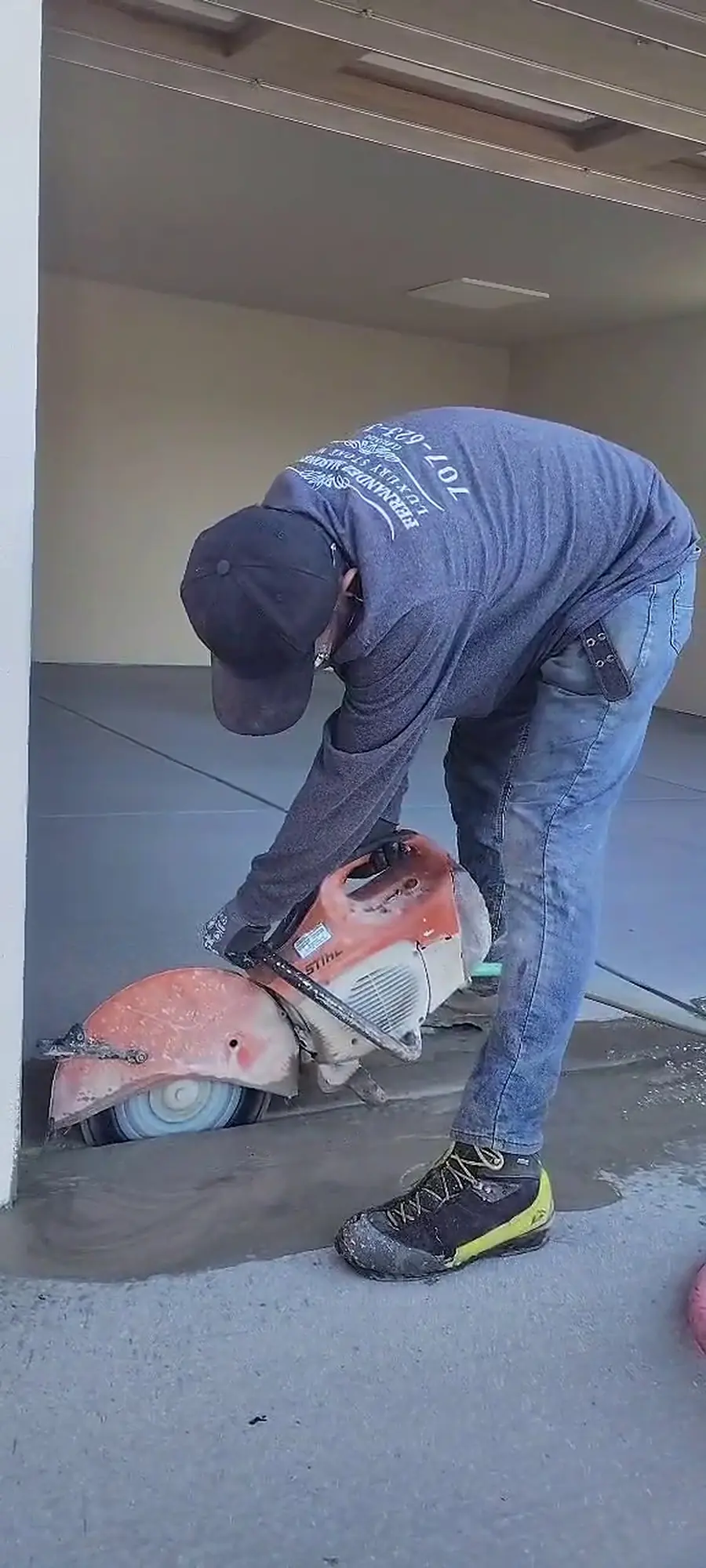 Crew member cutting concrete with a power saw